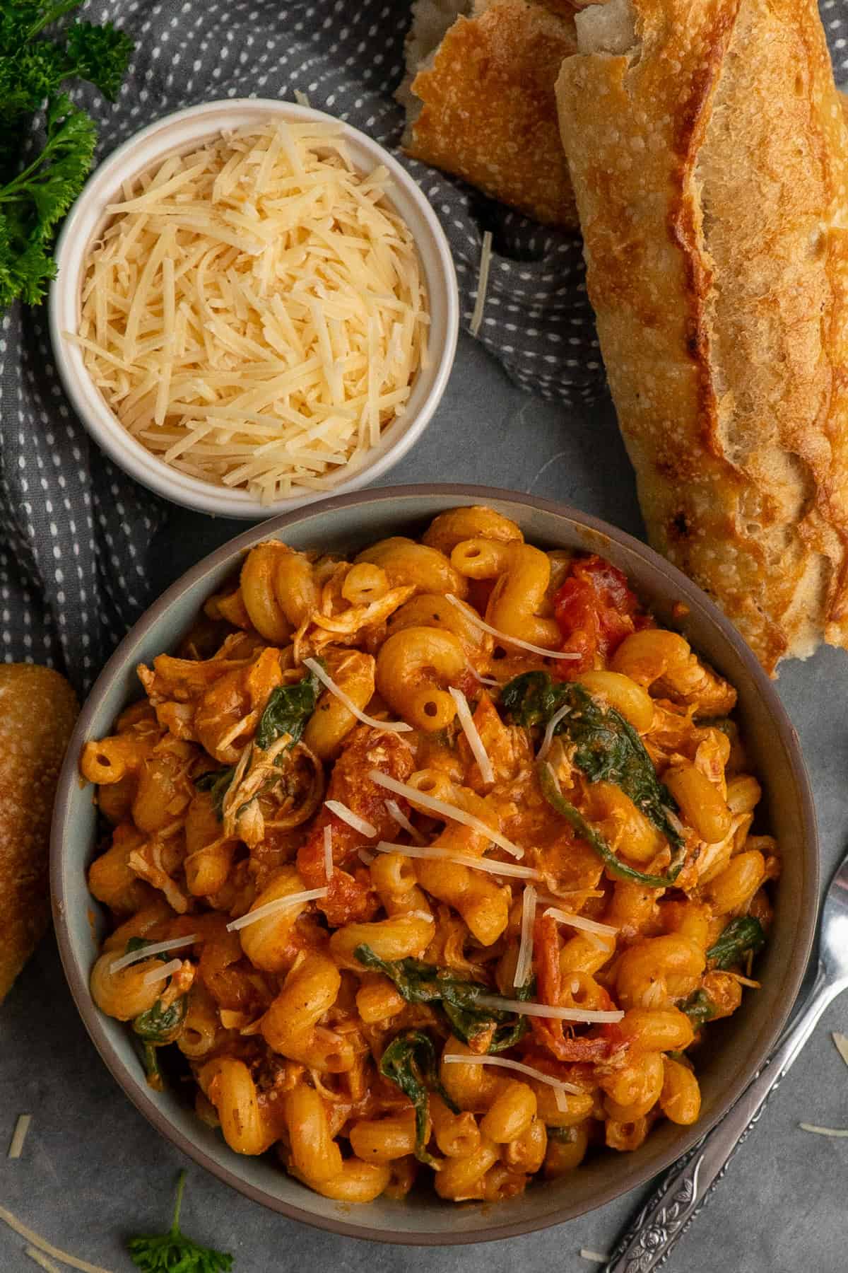 Crock pot marry me chicken pasta in a bowl with bread in the background. 
