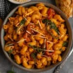 Crock pot marry me chicken pasta in a bowl with bread in the background.