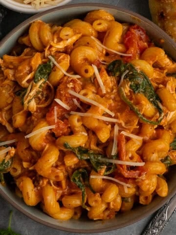 Crock pot marry me chicken pasta in a bowl with bread in the background.