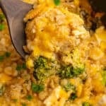 A wooden spoon holding a scoop of crock pot chicken broccoli and rice casserole.