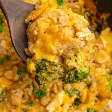 A wooden spoon holding a scoop of crock pot chicken broccoli and rice casserole.