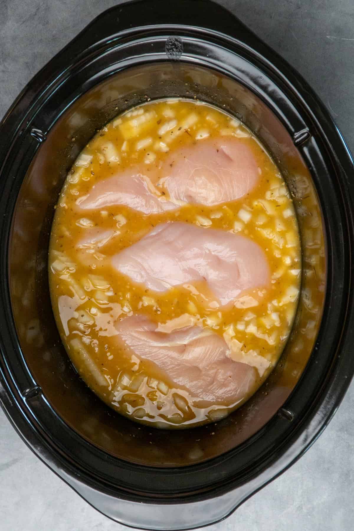 Three chicken breasts added to sauce ingredients.