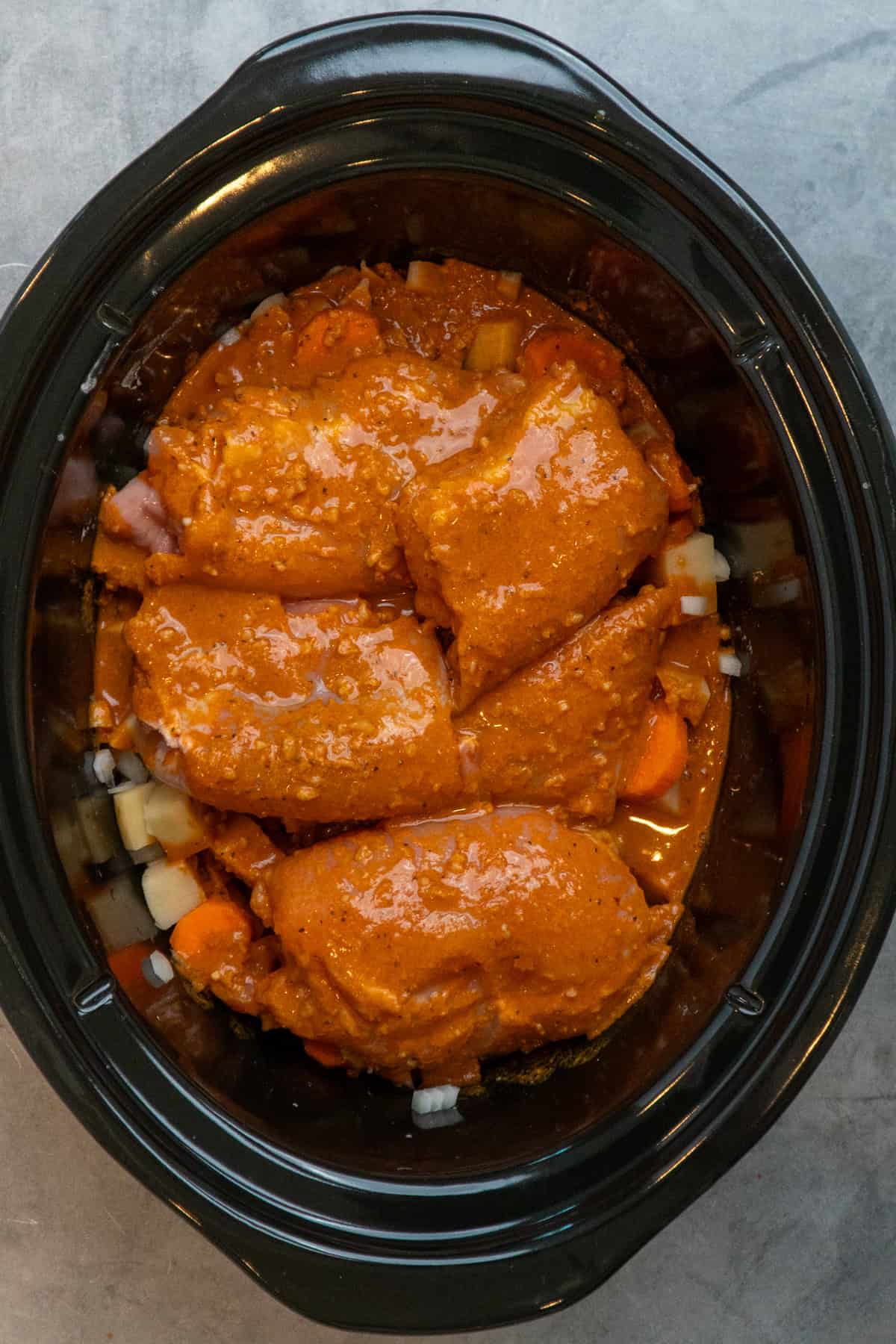 Chicken and vegetables coated with the sauce in the crockpot.