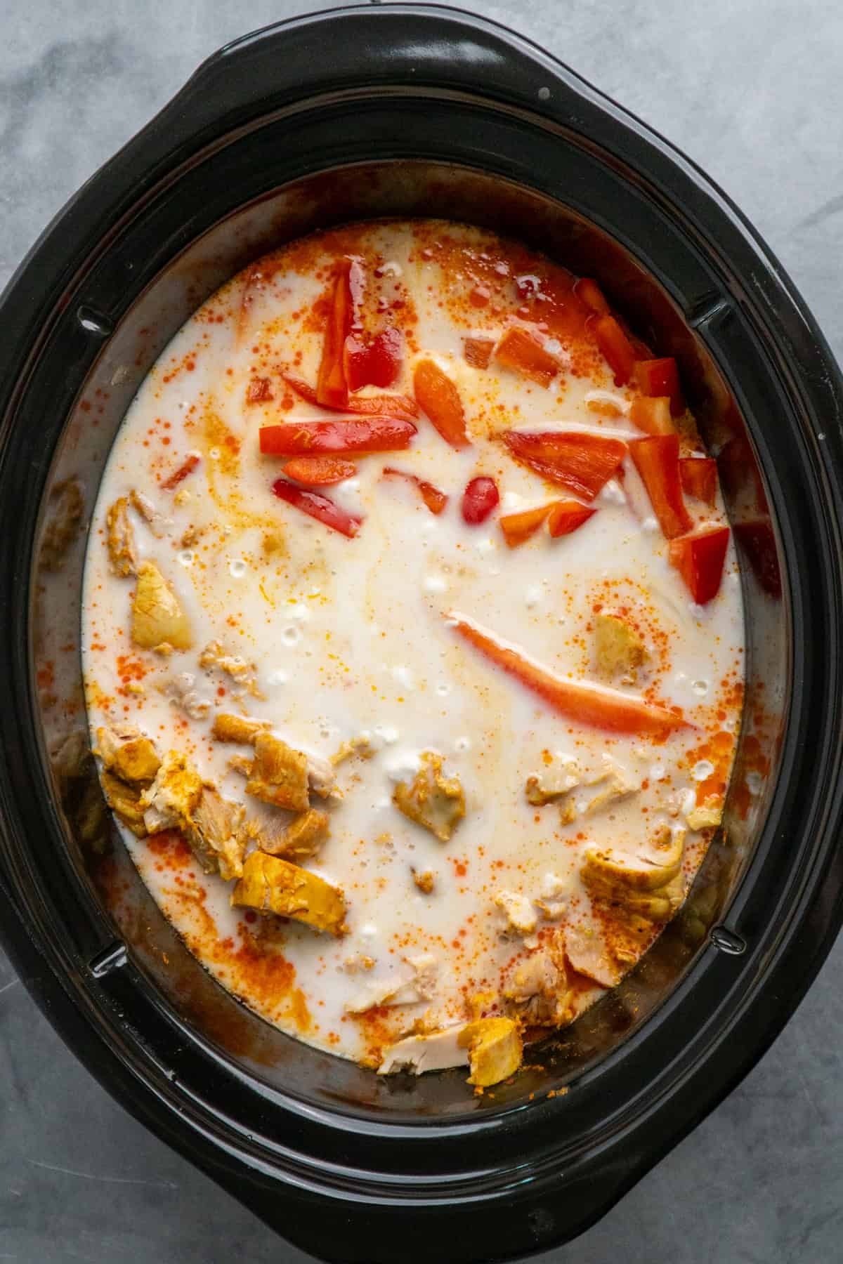 Coconut milk, chicken and bell peppers added to the slow cooker.