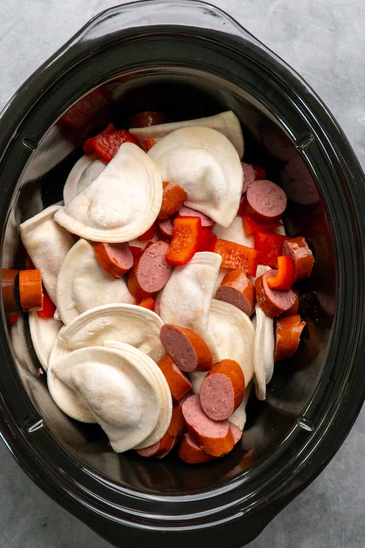 Pierogi, sliced kielbasa, and rell bell peppers in a crock pot.