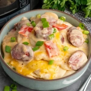 Crock pot pierogi casserole in a blue bowl and garnished with green onions.