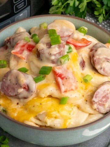 Crock pot pierogi casserole in a blue bowl and garnished with green onions.