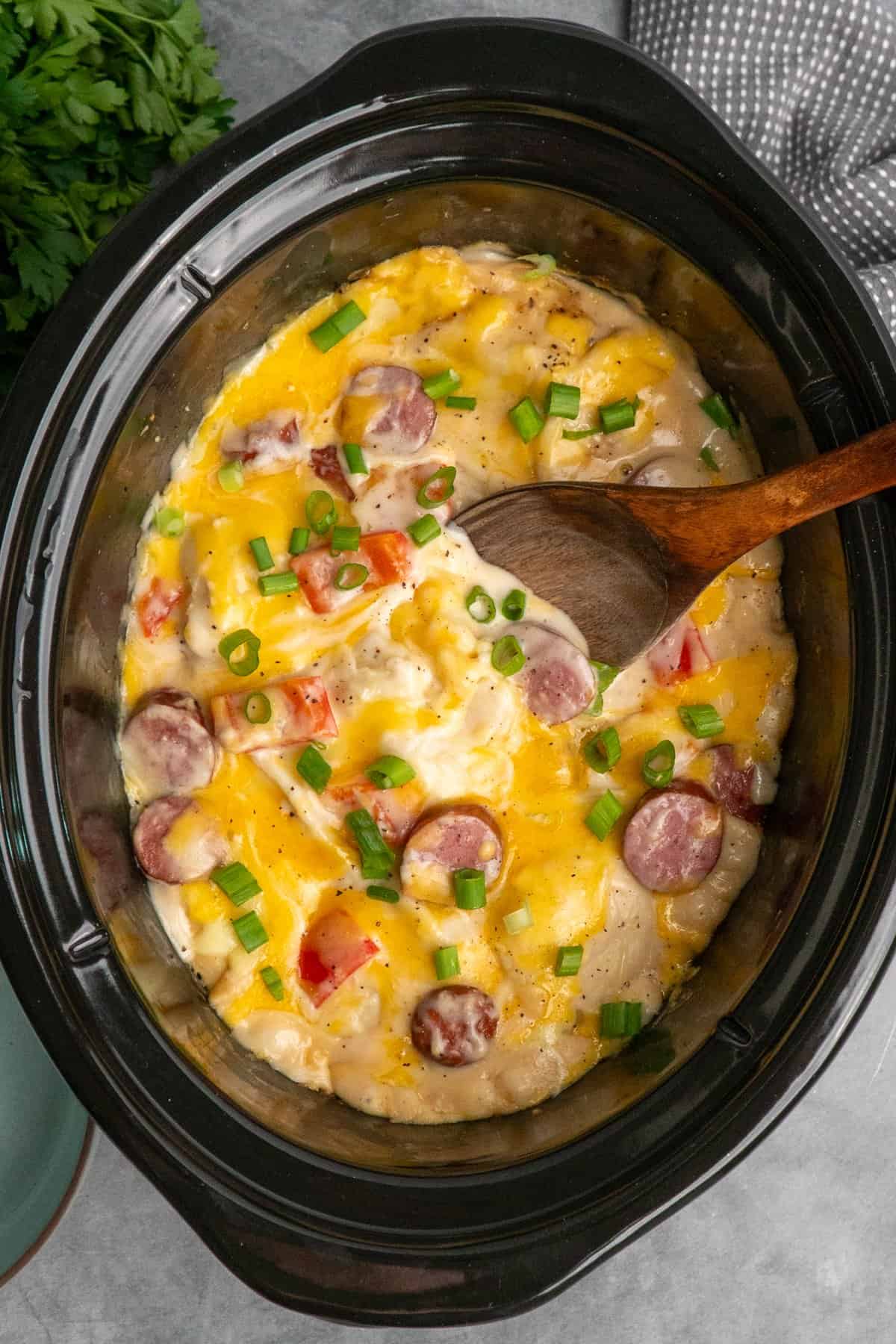 Crock pot pierogi casserole with a wooden spoon in it ready to be served.