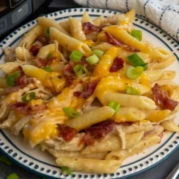 Crock pot crack chicken pasta on a plate topped with green onions.