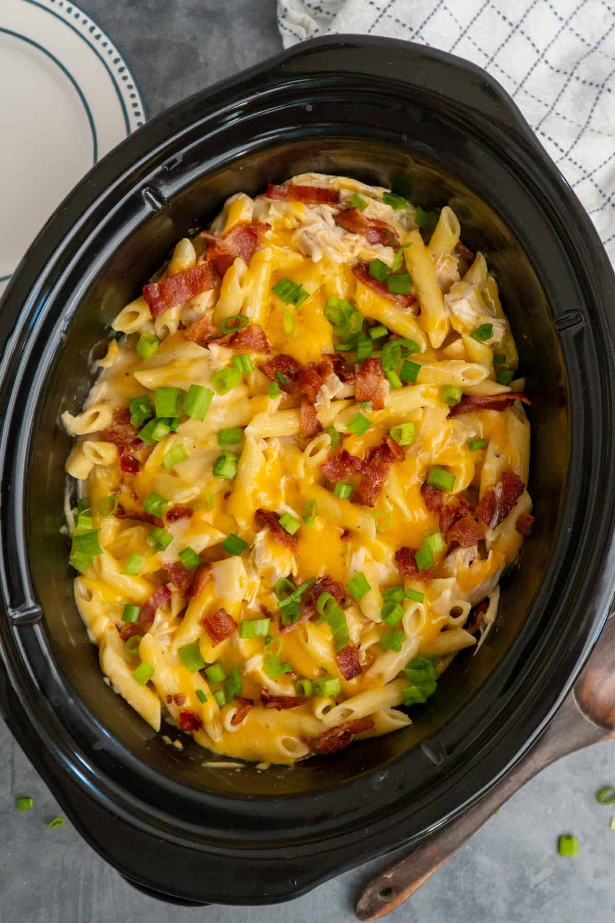 Finished crock pot crack chicken pasta topped with cheese, bacon and green onions.