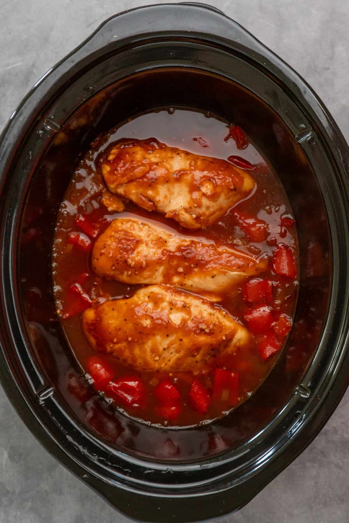Cooked pineapple BBQ chicken in a crock pot.