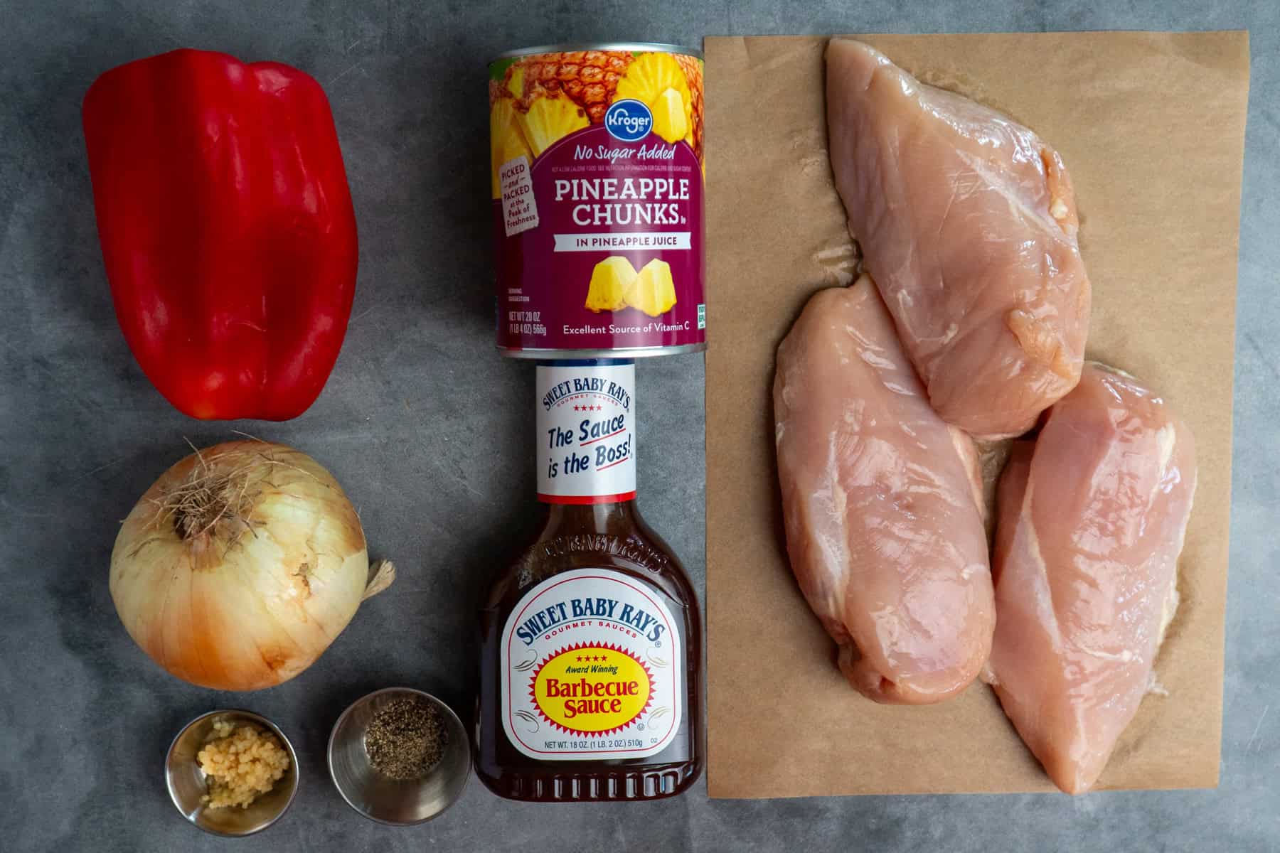 Ingredients to make pineapple BBQ chicken on a gray countertop. 