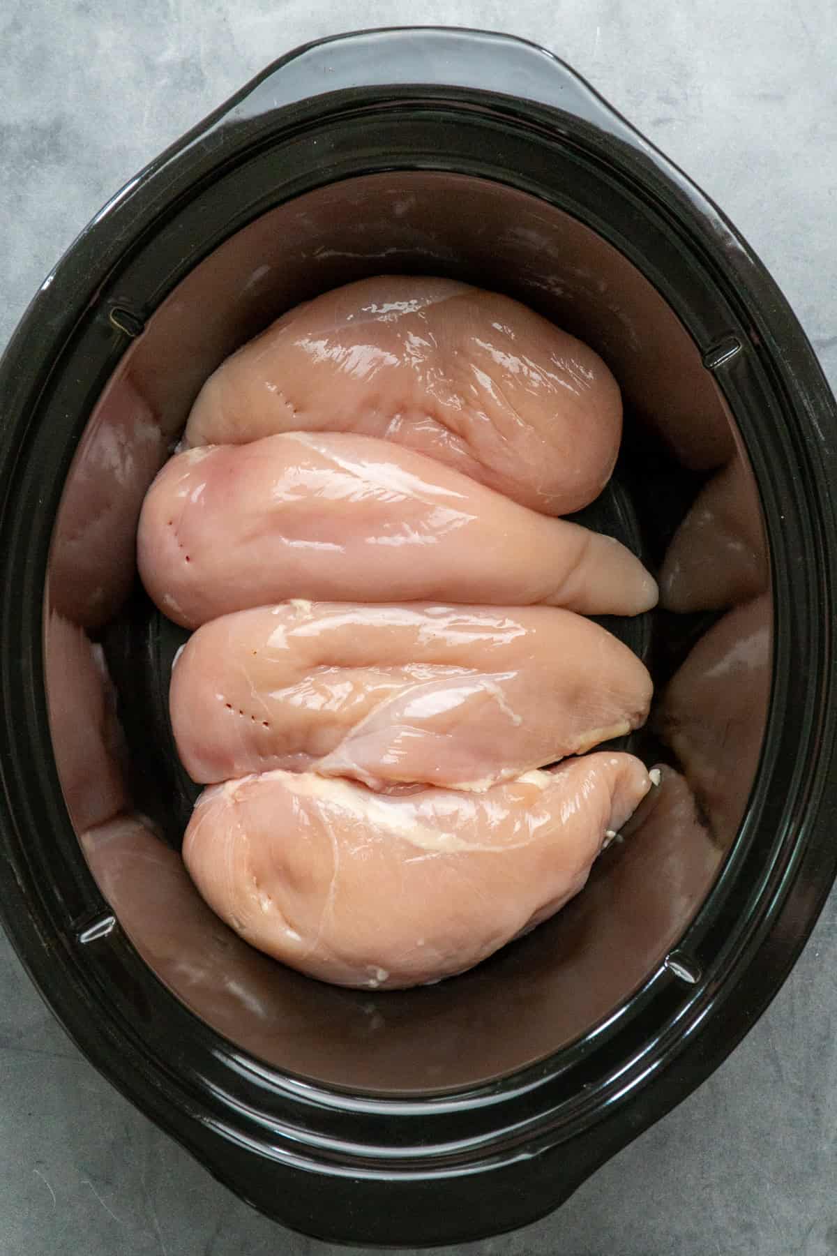 Four chicken breasts in a crock pot.