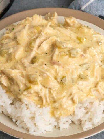 Crock pot green chile chicken over a plate of rice.