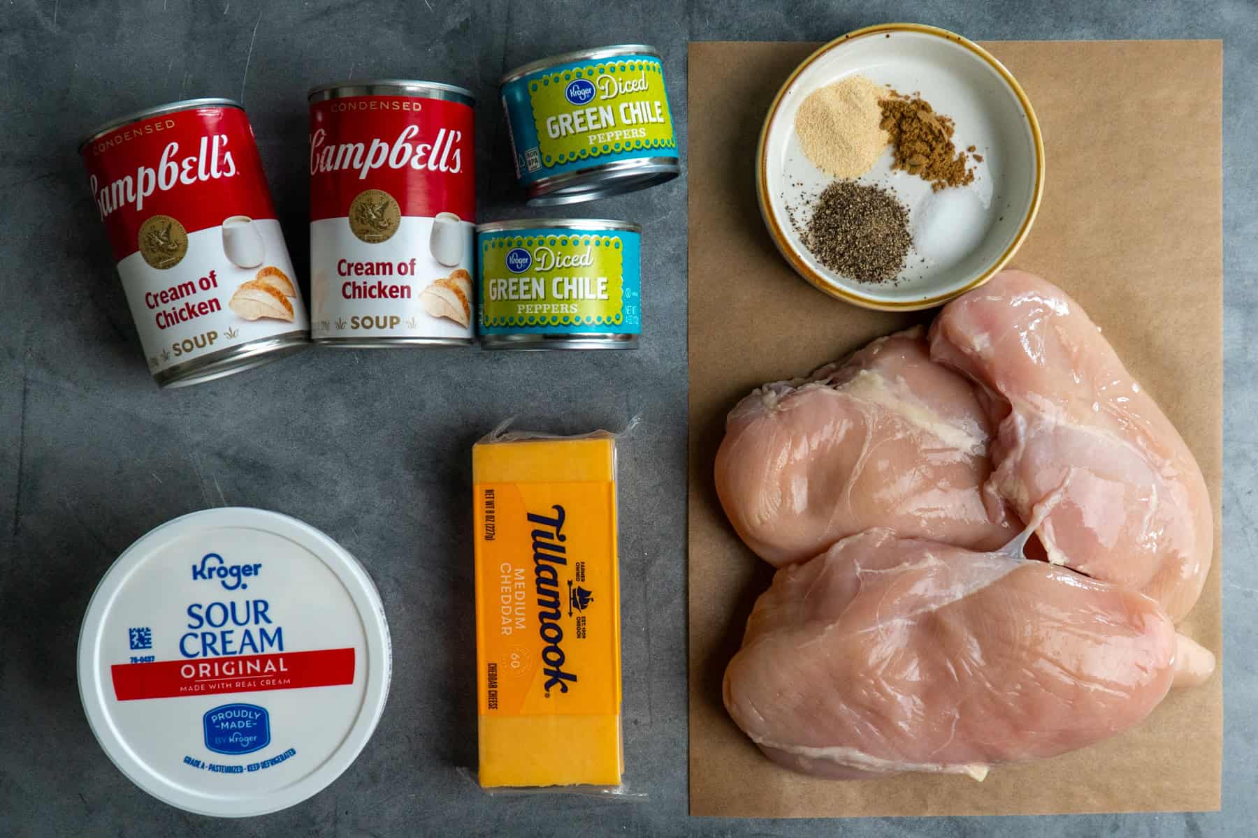 Ingredients to make green chile chicken on a gray countertop.