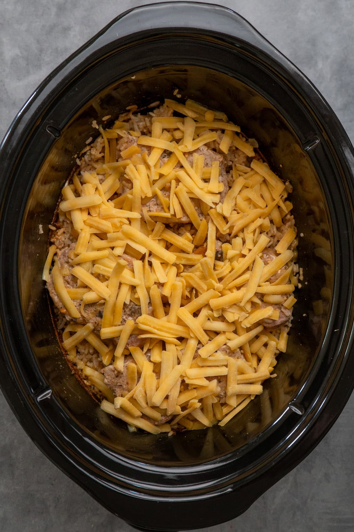 Cheddar cheese added to the pork chops and ready to be melted.