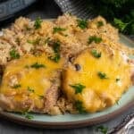 Crock pot pork chops and rice on a plate garnished with chopped parsley.