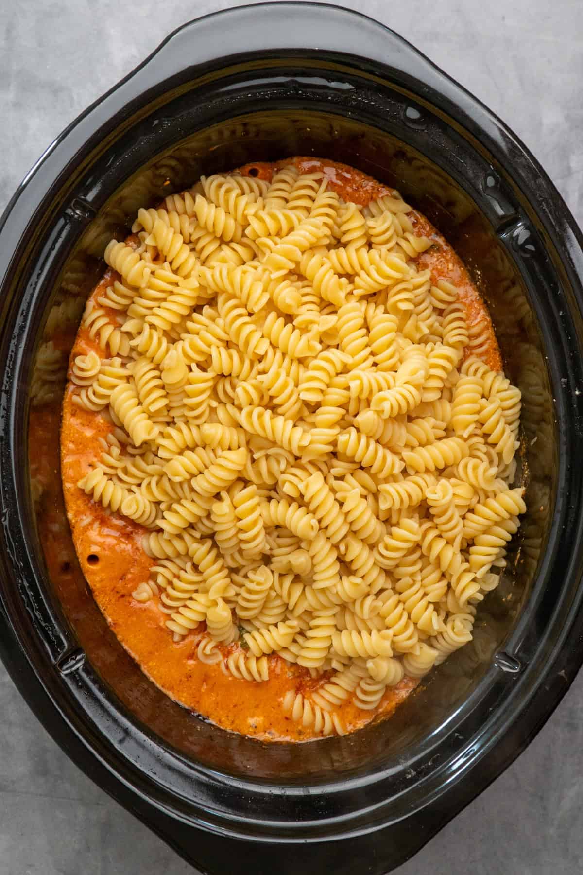 Rotini pasta added to the slow cooker.