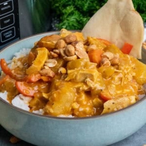 Coconut curry chicken over a bowl of rice with naan bread.
