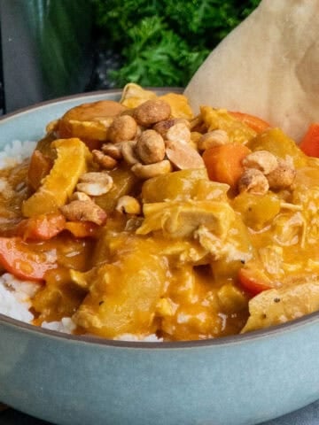 Coconut curry chicken over a bowl of rice with naan bread.