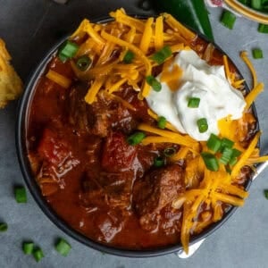 Slow Cooker Texas chili in a bowl and topped with grated cheese and sour cream.