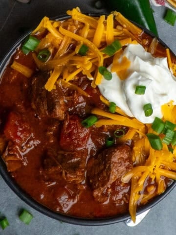Slow Cooker Texas chili in a bowl and topped with grated cheese and sour cream.