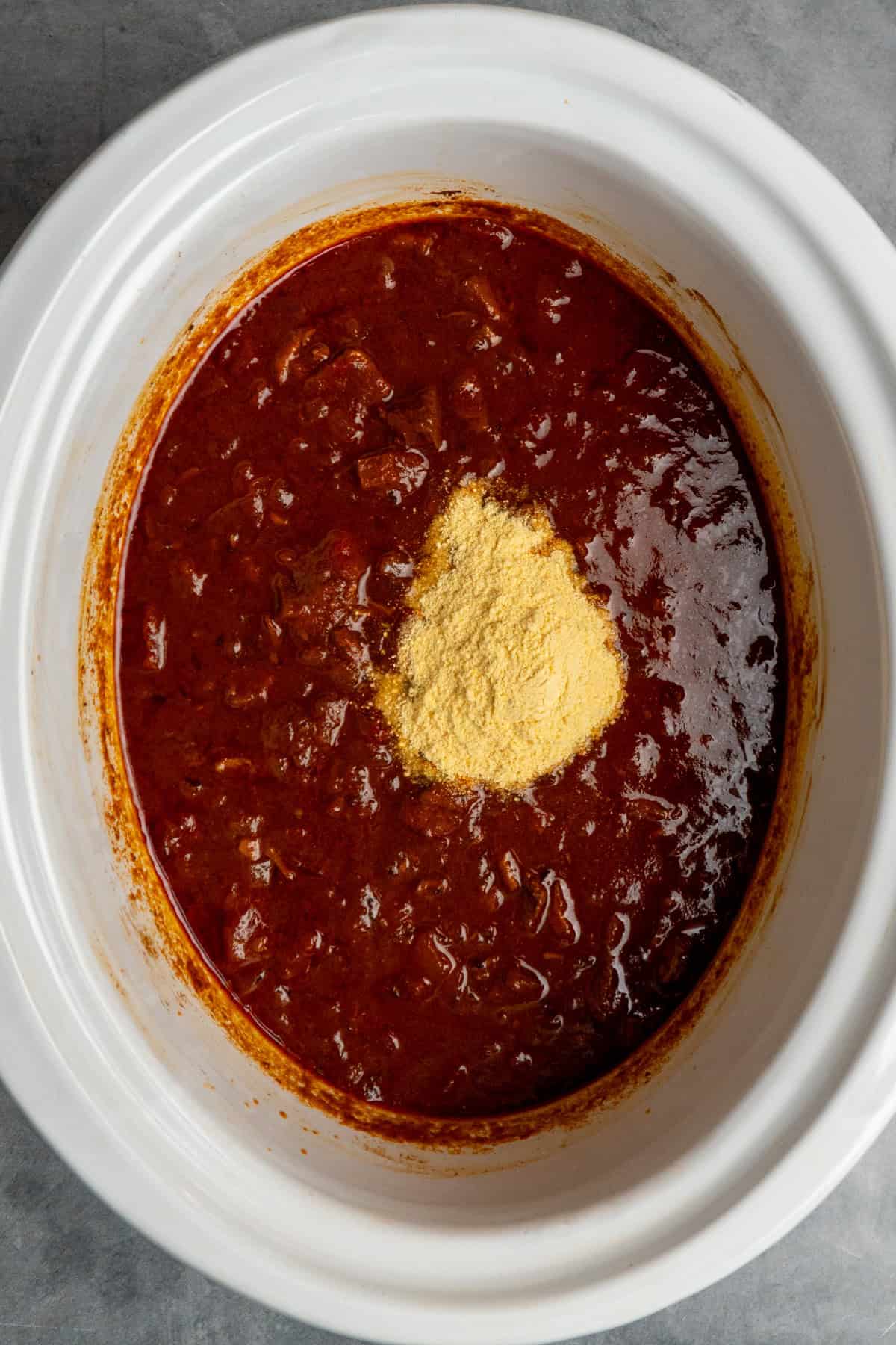 Masa harina added to chili ready to be stirred in to thicken it.