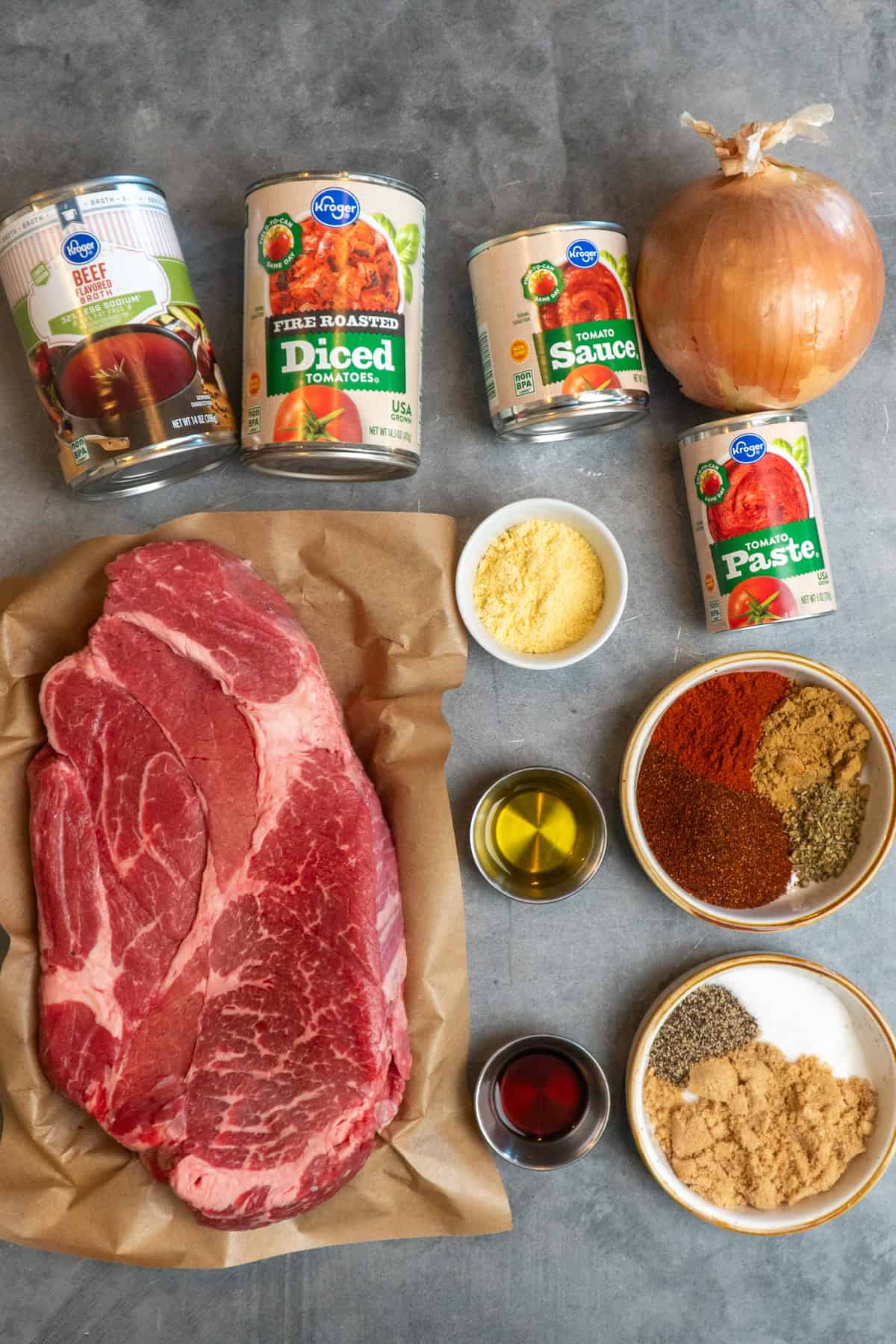 All the ingredients to make Texas chili on a gray countertop.