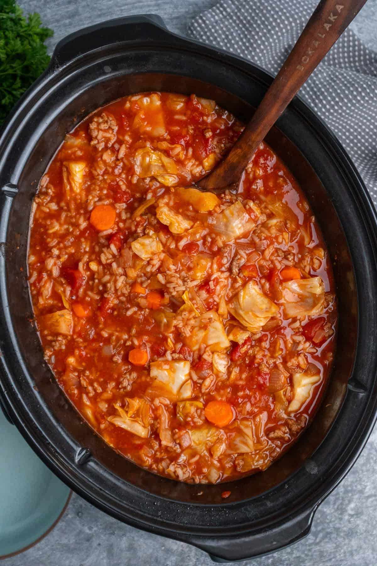 Slow cooker cabbage roll soup with a wooden ladle in it ready to be served.