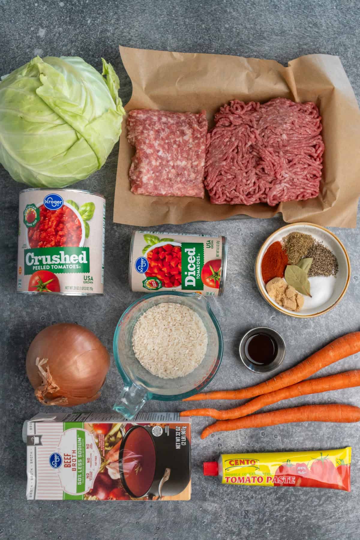 All the ingredients to make cabbage roll soup on a gray countertop.