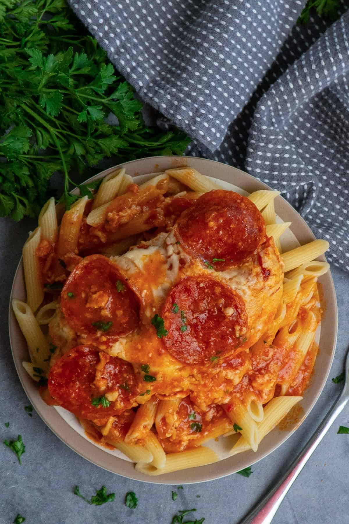 Pizza chicken over a plate of pasta noodles.