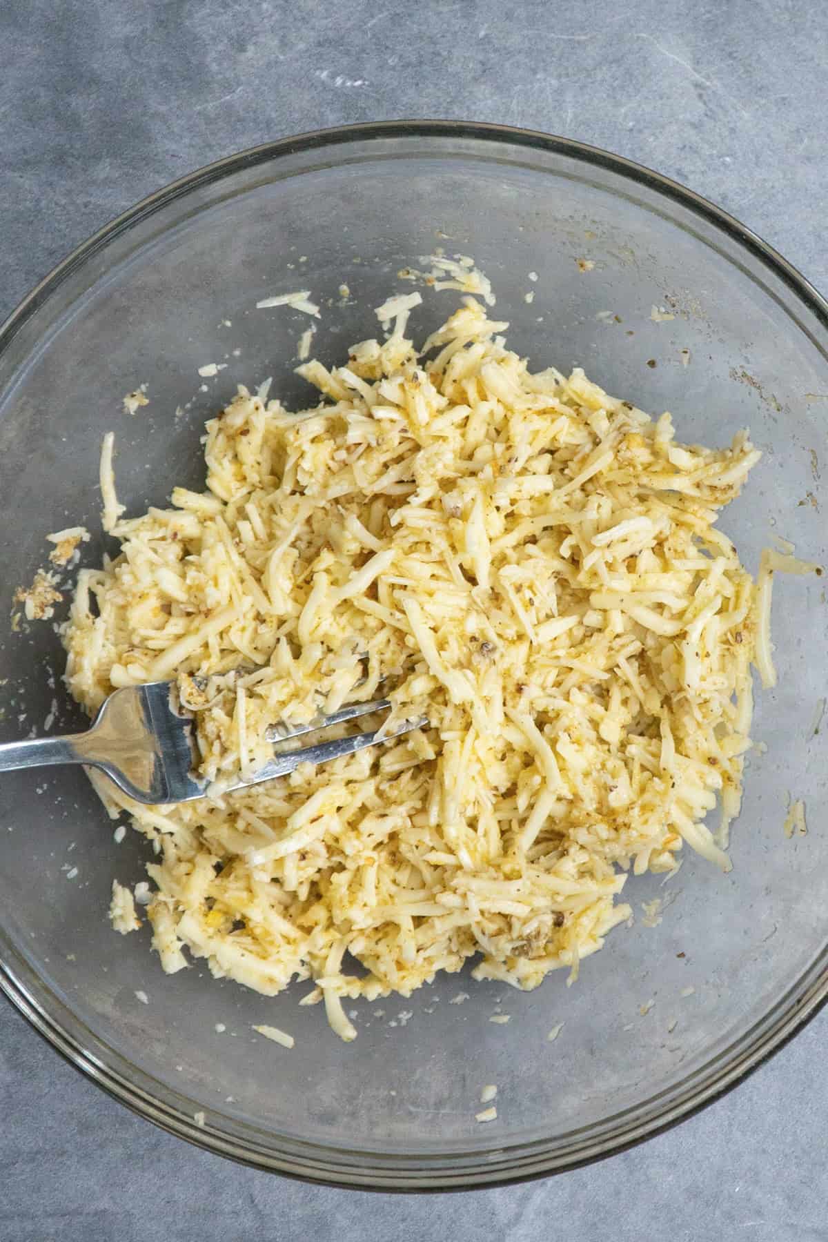 Parmesan cheese, mozzarella cheese, eggs, and seasonings mixed together in a clear bowl.