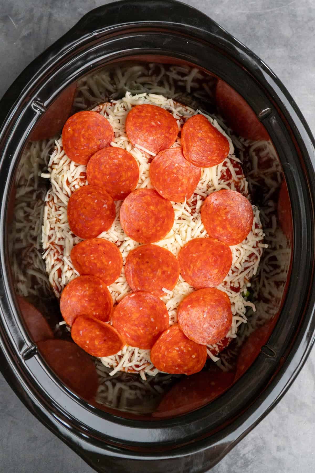 Stuffed chicken, cheese and pepperonis added to a slow cooker.