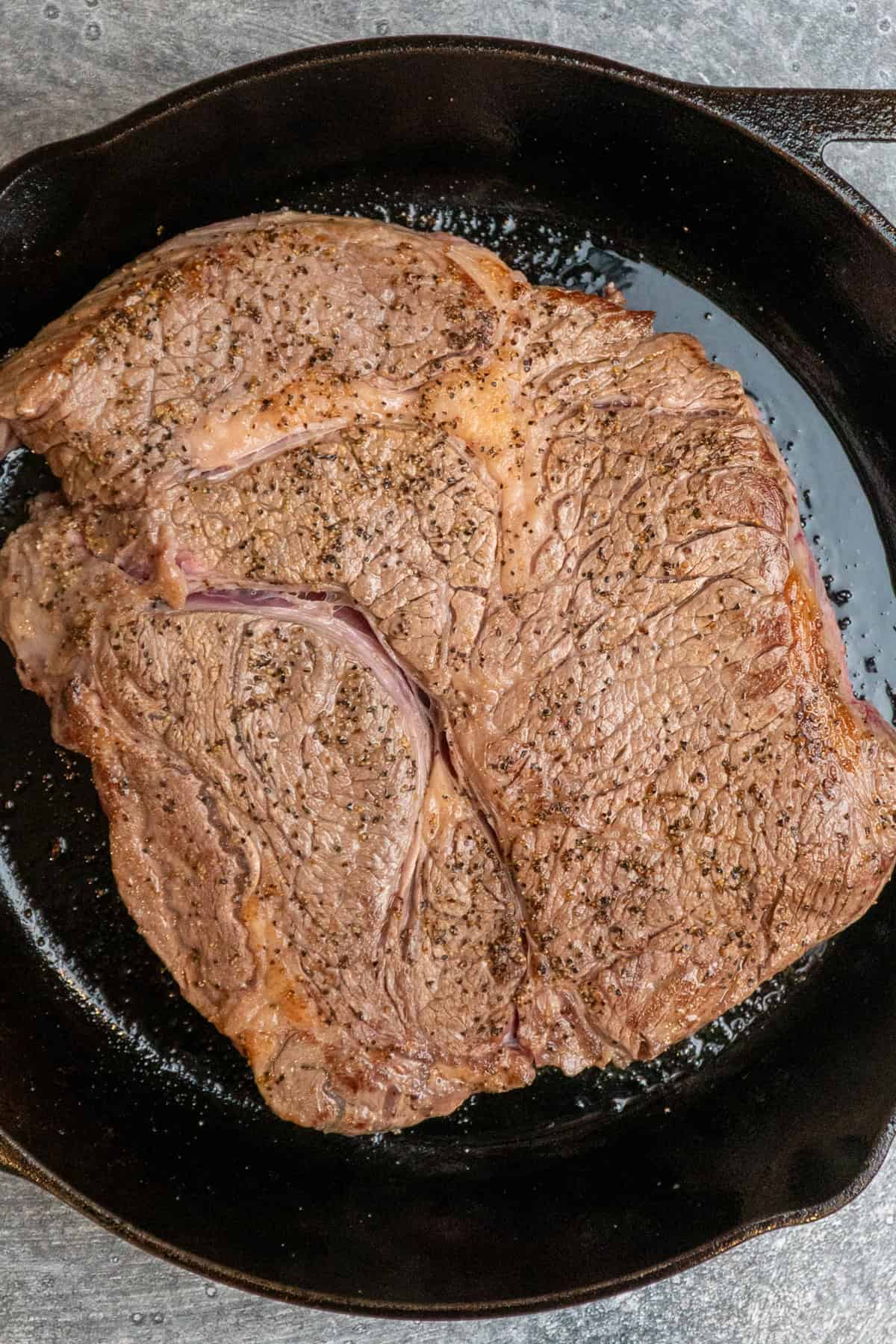 A chuck roast seared in a cast iron skillet.