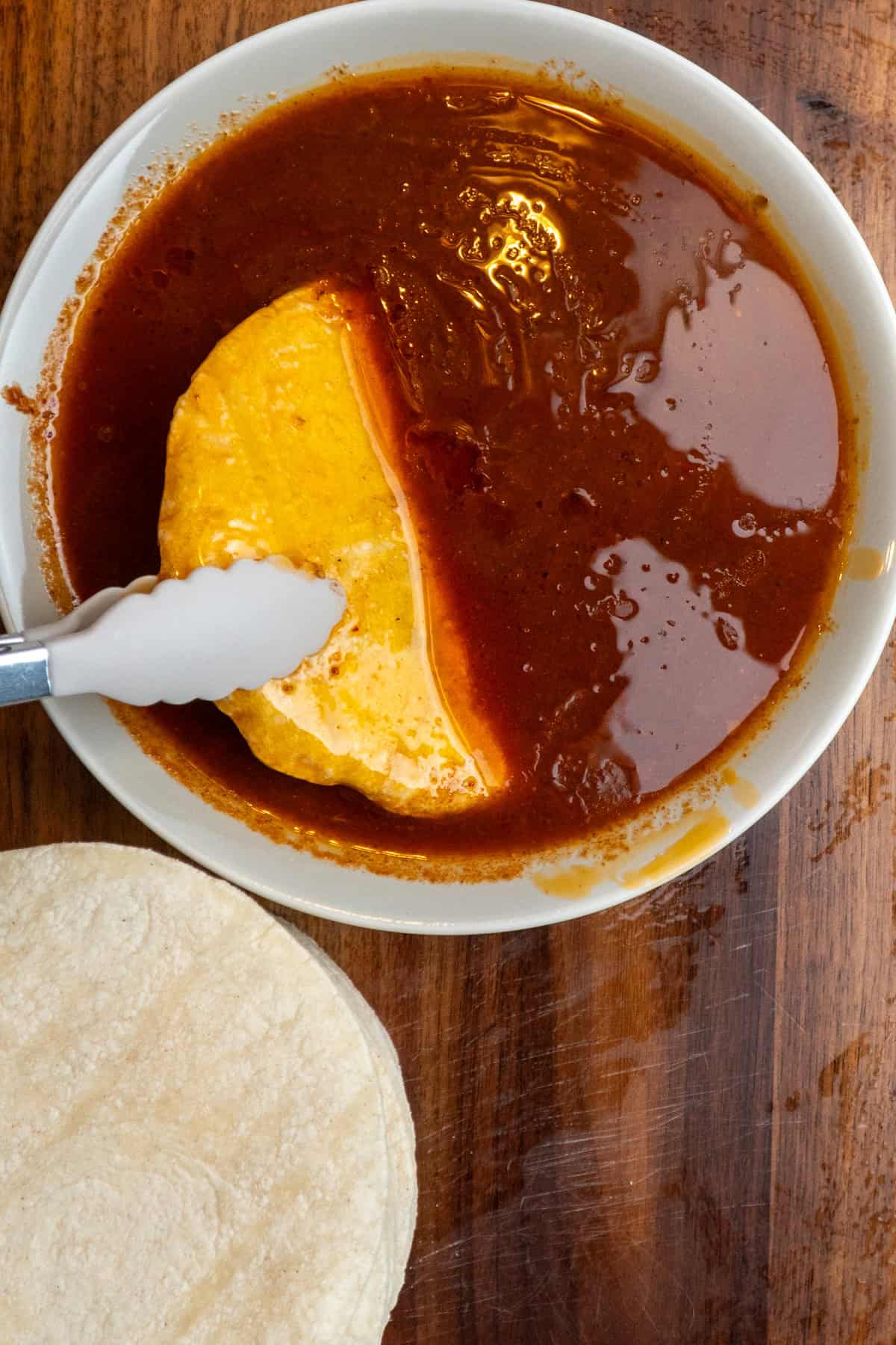 A corn tortilla dipped into the birria broth.