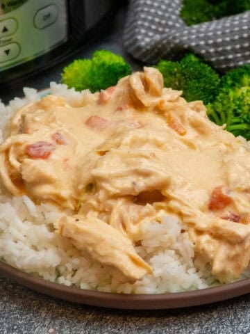 Cheesy chicken over a plate of rice with broccoli.