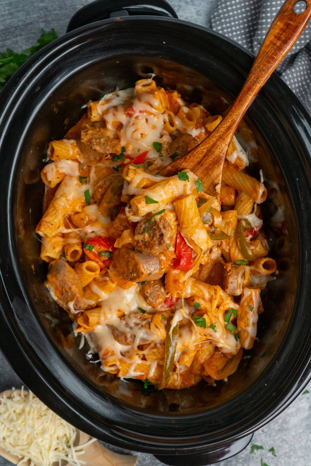 A wooden spoon holding a scoop of Italian sausage pasta ready to be served.