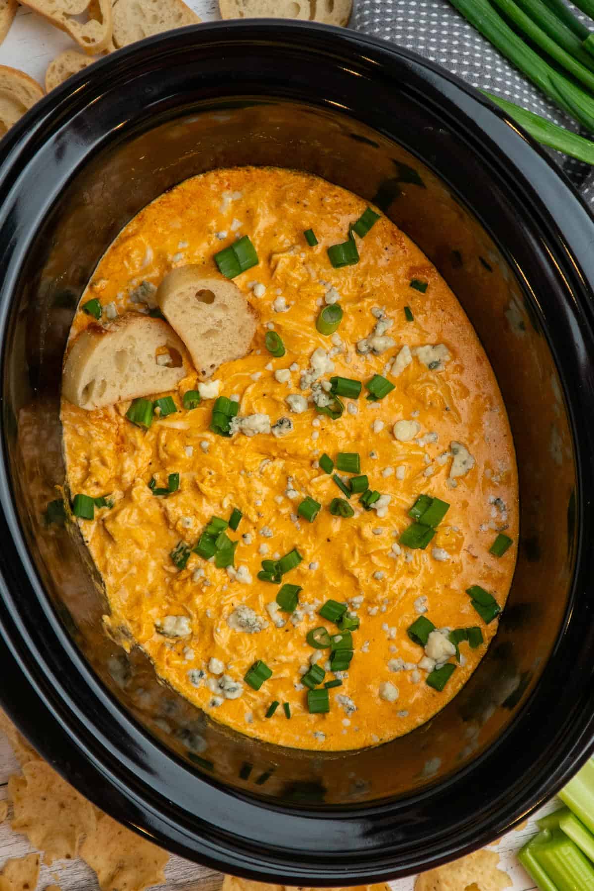 Crock Pot buffalo chicken dip garnished with green onions and blue cheese crumbles.