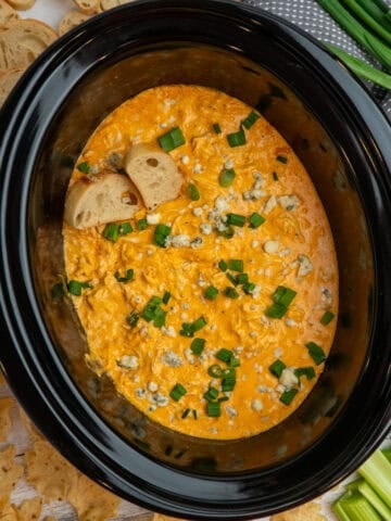 Crock Pot buffalo chicken dip garnished with green onions and blue cheese crumbles.