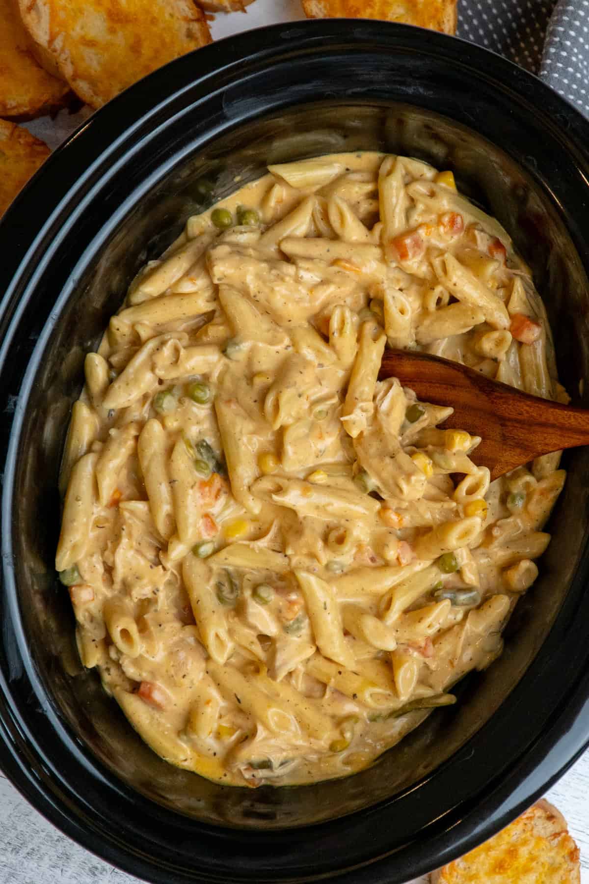 A wooden spoon mixing crock pot chicken pot pie pasta.
