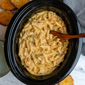 Crock Pot chicken pot pie pasta being mixed with a wooden spoon.
