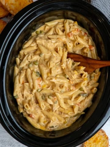 Crock Pot chicken pot pie pasta being mixed with a wooden spoon.