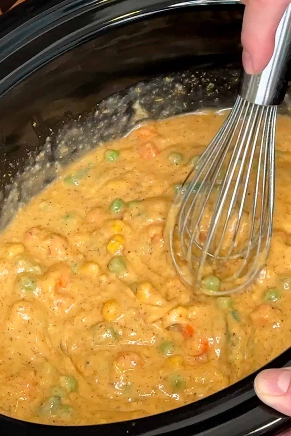 Chicken broth, chicken soup, seasonings, and mixed vegetables whisked together in a crock pot.