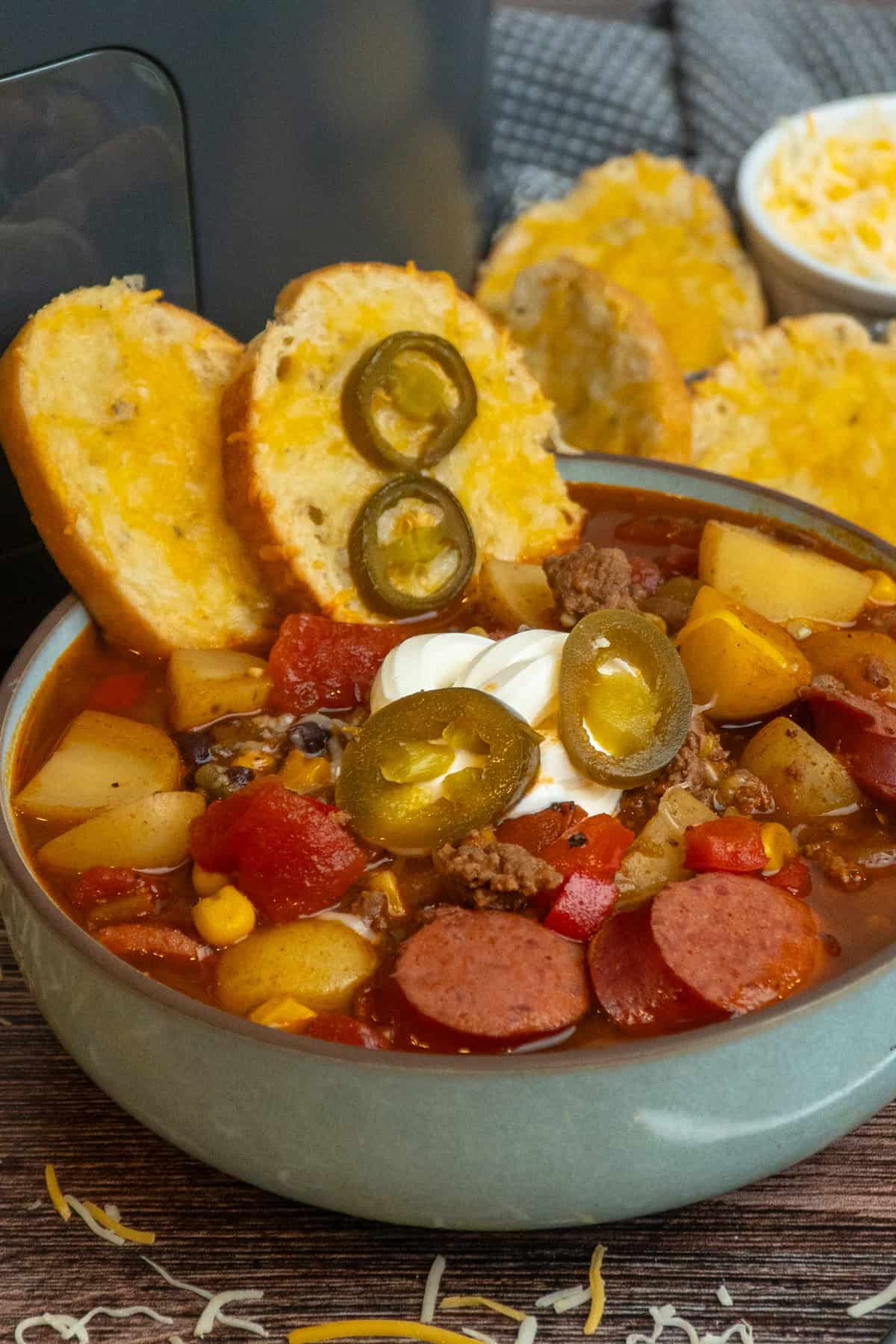 Cowboy soup in a bowl with cheesy bread dipped in it.