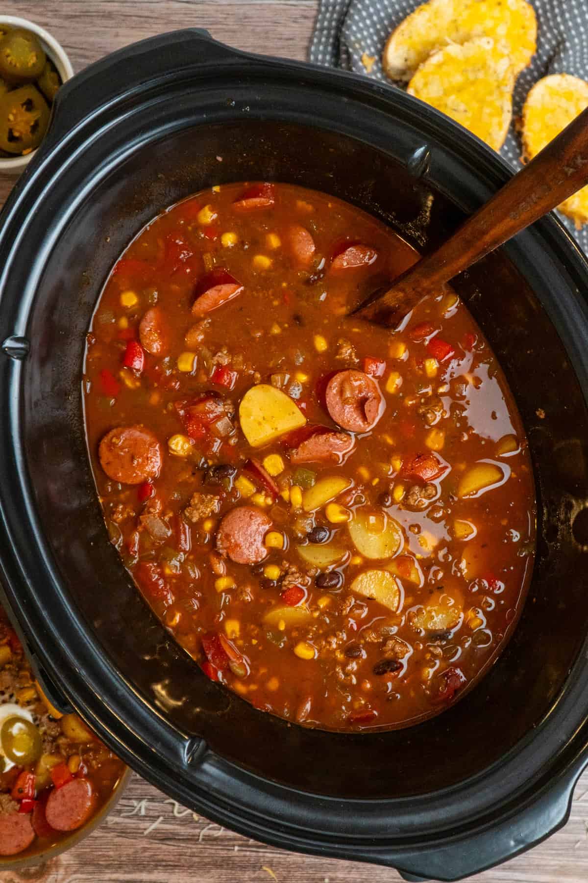 A wooden ladle in crock pot full of cowboy soup ready to be served.