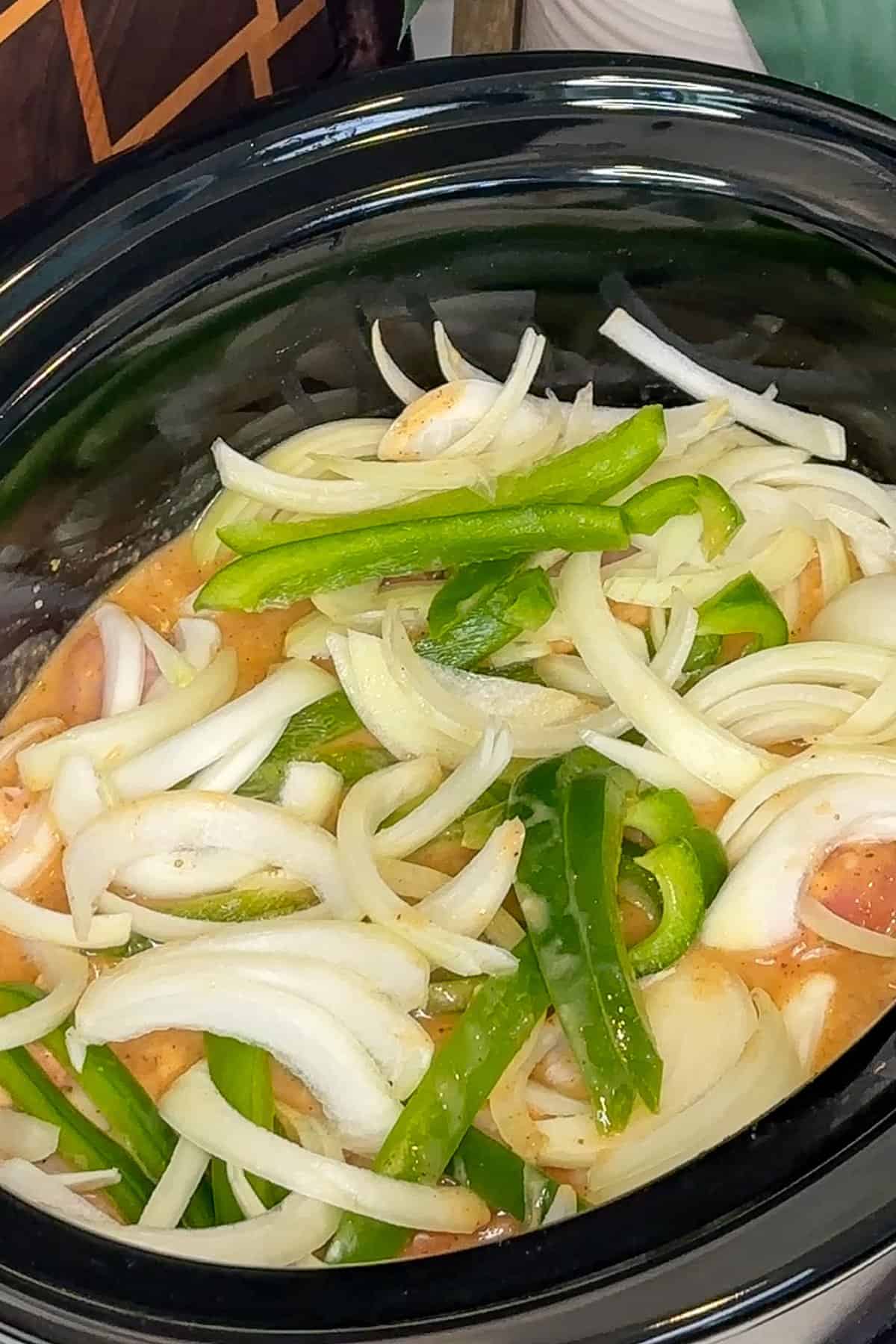 Sliced onions and green bell peppers added on top of the chicken.