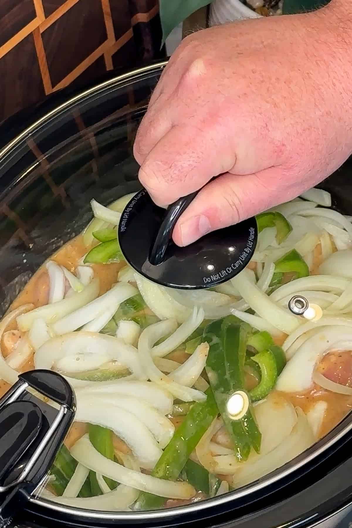 A lid being placed on the crock pot so the chicken legs can be cooked.
