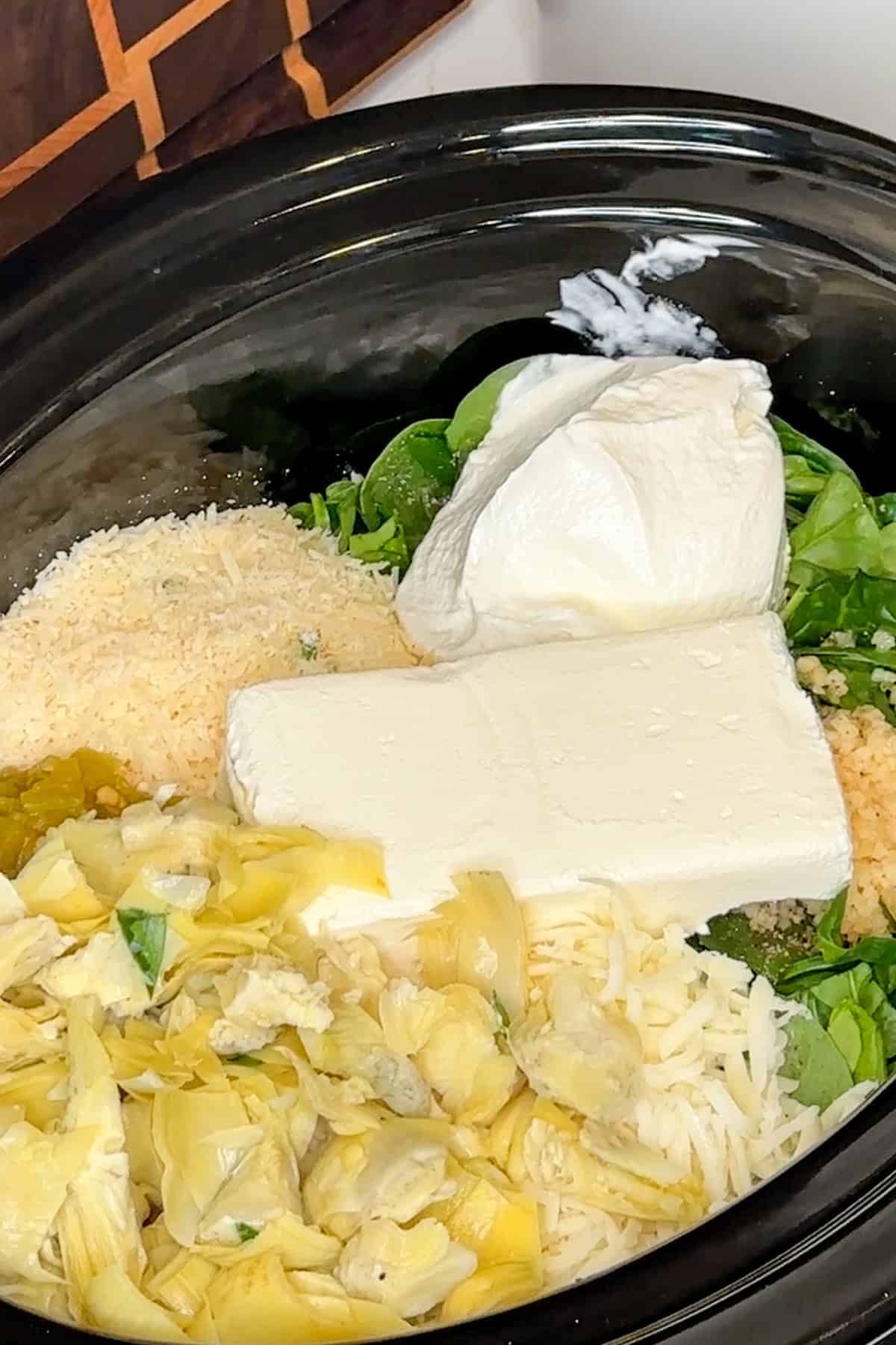 Cream cheese, sour cream, artichoke hearts, cheeses, and seasonings added to the spinach.