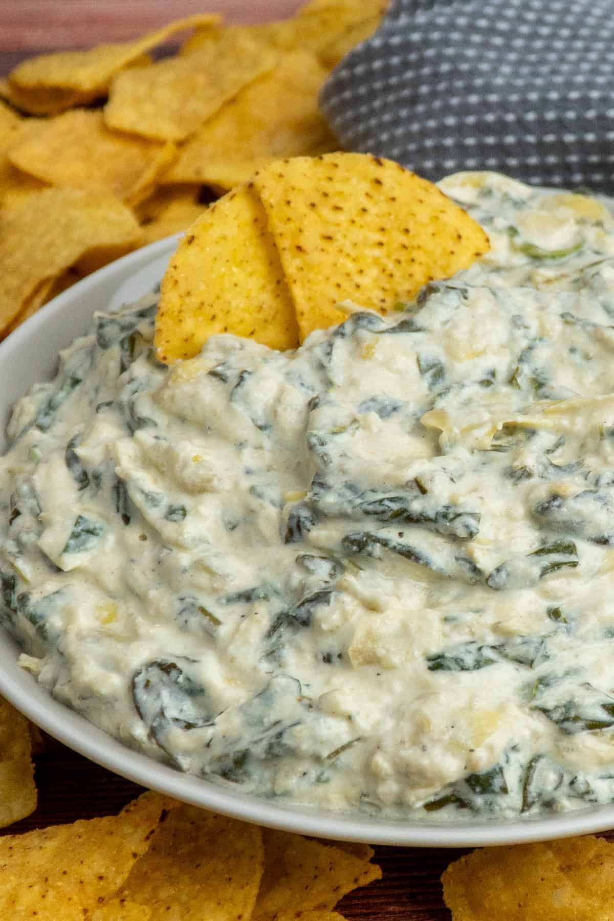 Spinach artichoke dip in a bowl with two chips in it.