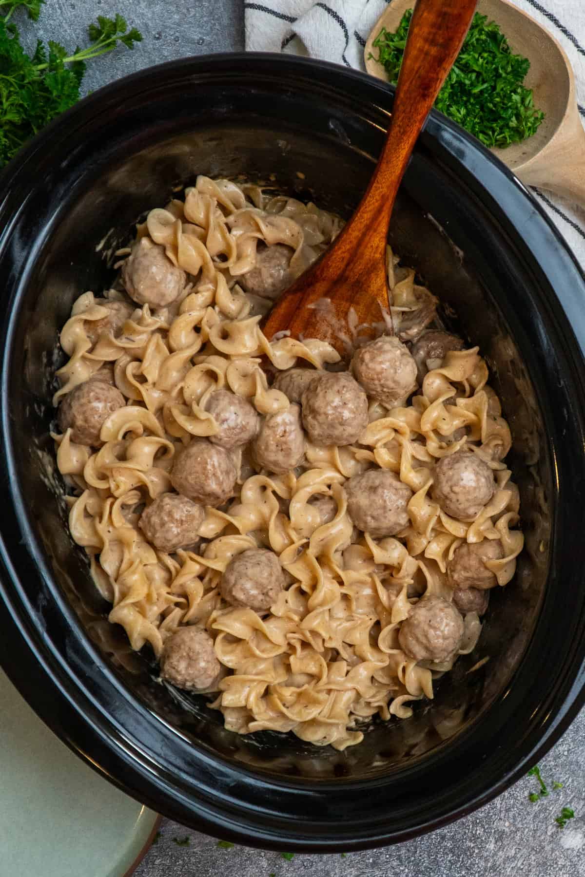 Crock Pot Swedish meatballs with a wooden spoon in it ready to be served.